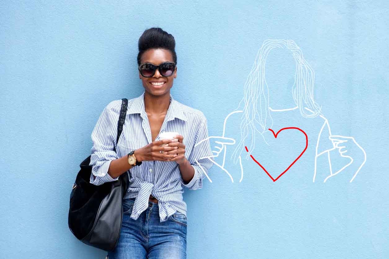 Smiling woman standing beside a heart mural